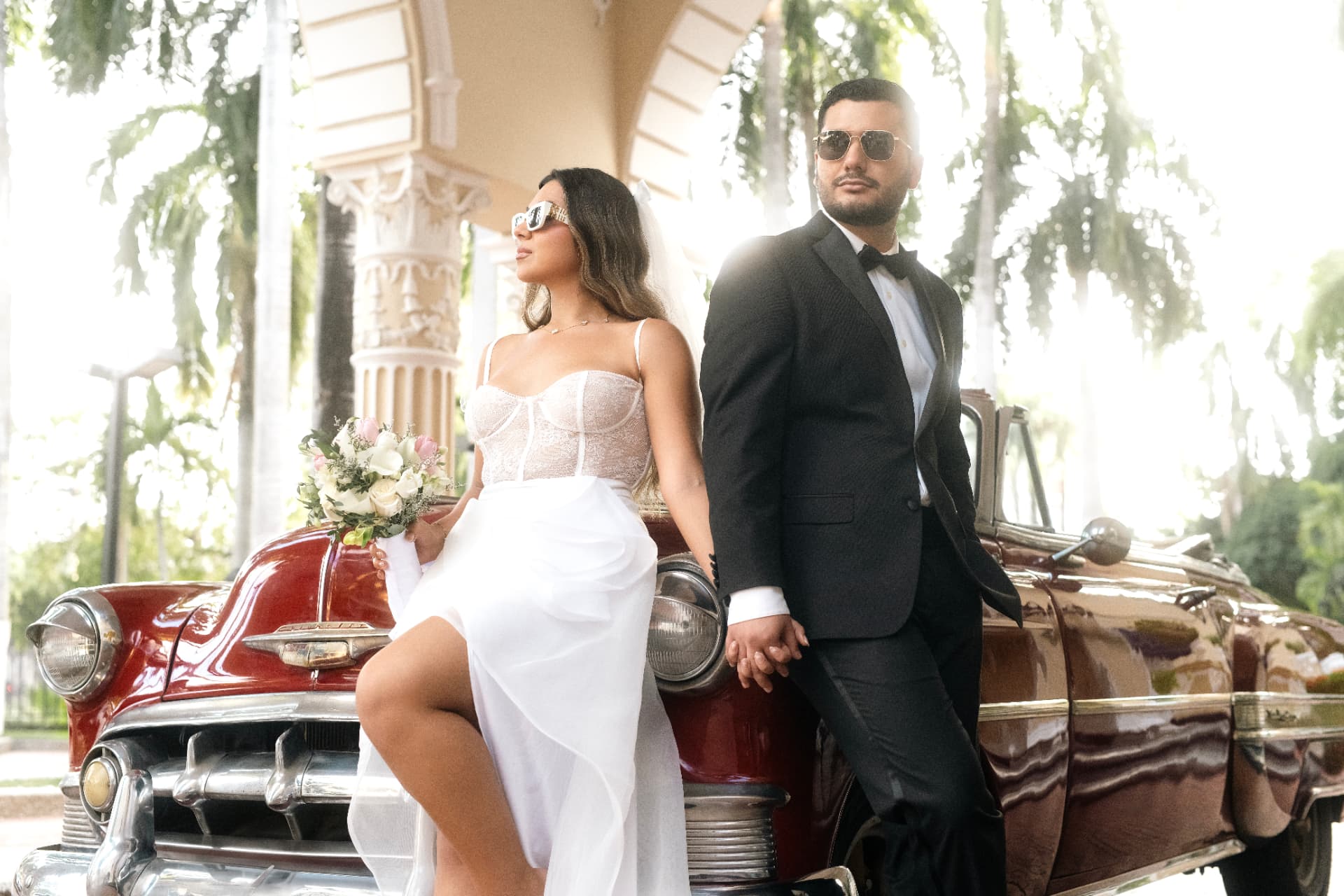 Angie Paulet y Juan Diego junto al auto clásico entre palmeras